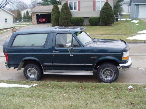 1995 Ford Bronco - This 1995 Ford Bronco is seen from the side, parked on a street with a house and garage in the background.