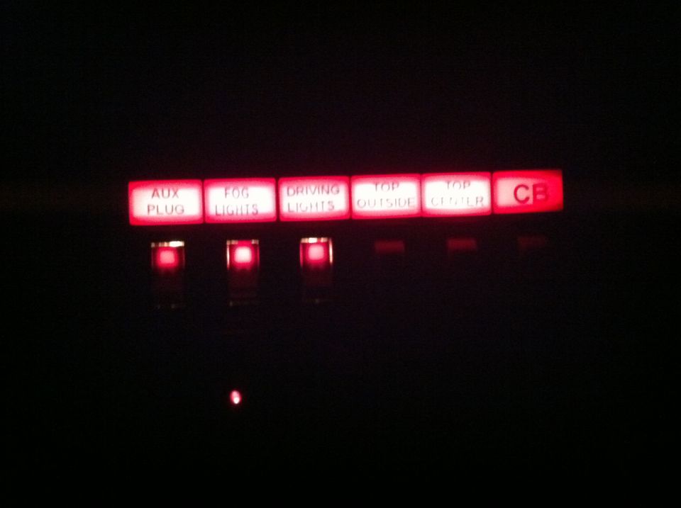 Illuminated red dashboard buttons with labels: AUX PLUG, FOG LIGHTS, DRIVING LIGHTS, TOP OUTSIDE, TOP CENTER, CB.
