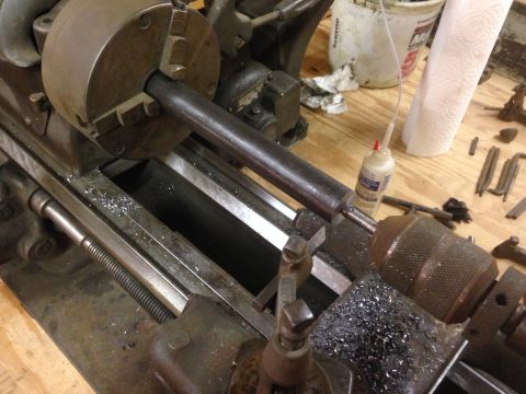1979 Ford Bronco - A close-up view of a metal lathe with a workpiece held in the chuck and metal shavings scattered on the machine bed. A bottle of lubricant…