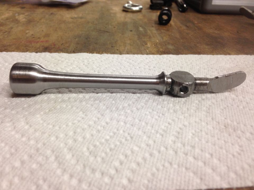 Custom metal part with brushed finish on a white paper towel.