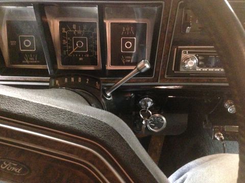 1979 Ford Bronco - The interior of a classic Ford truck or SUV shows the dashboard with gauges, a radio, and the gear shifter. The Ford logo is visible on the…