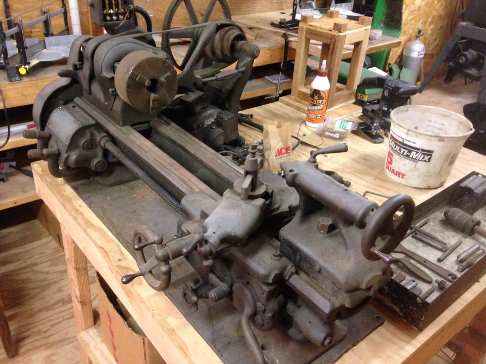 Workshop scene with a metal lathe, tools, bucket, and glue.