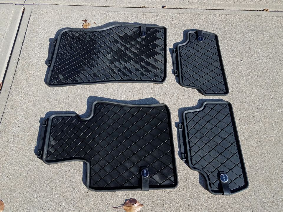 Four black MINI Cooper all-weather floor mats with diamond pattern on concrete.