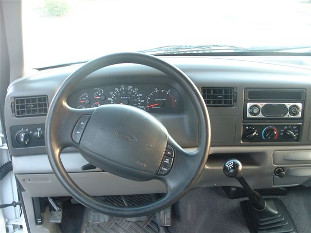Dashboard view of a 1999 Ford F-250 Super Duty truck, showing the steering wheel, instrument cluster, and center console with radio and climate controls