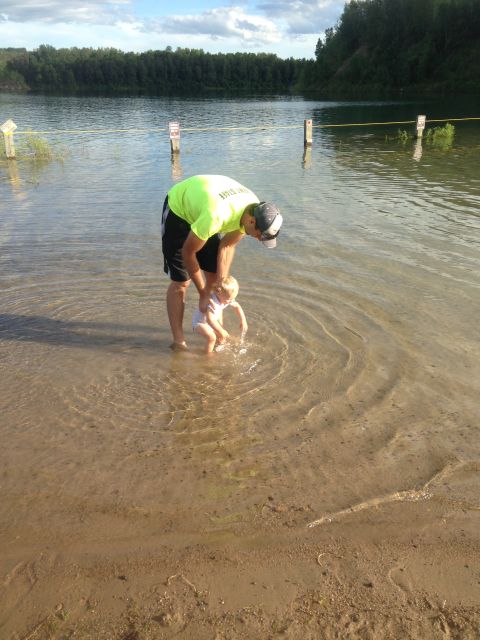 1979 Ford Bronco - A man in a neon green shirt and a child are standing in shallow water near a sandy shore.