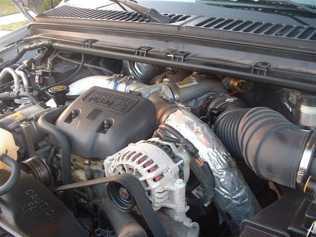 Engine bay with "TURBO DIESEL" cover, alternator, and intake piping