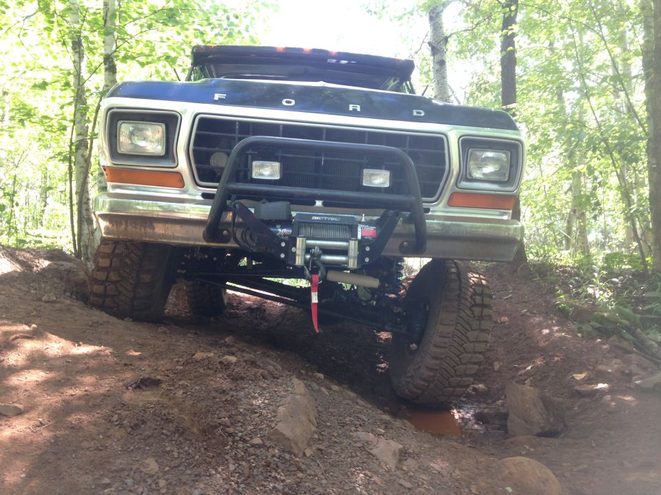 Front view of a dark blue Ford Bronco on a dirt trail, with a winch on the bull bar.