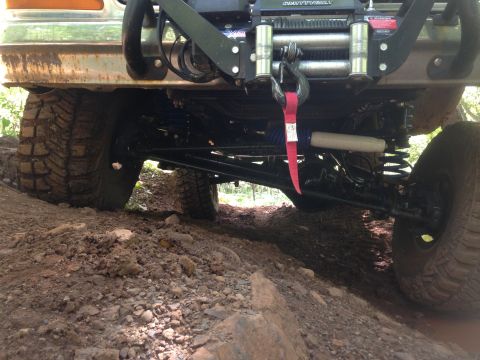 1979 Ford Bronco - The rear underside of a lifted off-road vehicle, likely a 1979 Ford Bronco, is shown angled on a dirt trail. Visible modifications include…