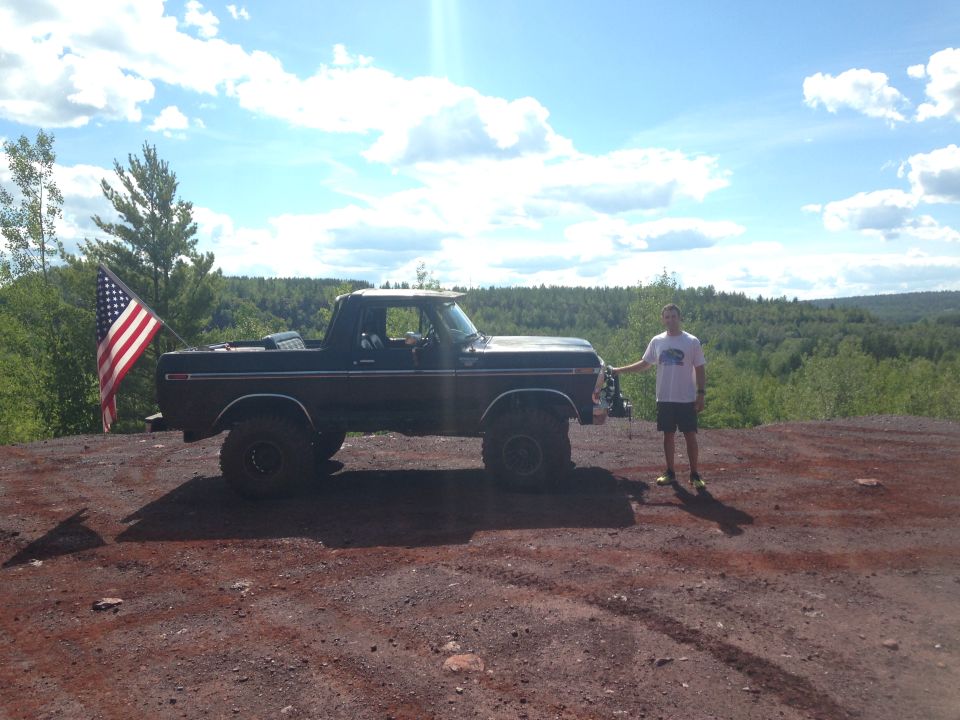Man standing next to a dark Ford Bronco with an American flag.