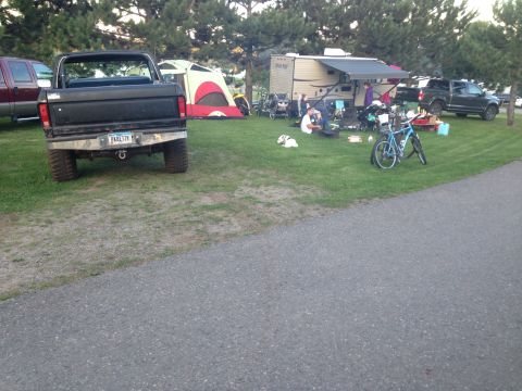1979 Ford Bronco - The rear of a black Ford pickup truck is shown parked on grass at a campsite. A tent and RV are visible in the background.