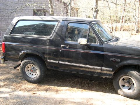 1994 Ford Bronco - Side profile of a black 1994 Ford Bronco, showing its distinctive body style and removable hardtop.