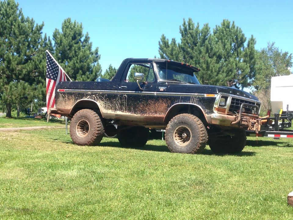 Mud-covered black 1979 Ford Bronco with an American flag.