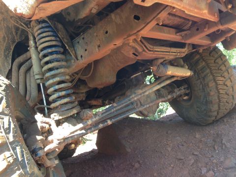 1979 Ford Bronco - Underside view of a heavily modified 4x4 vehicle, likely an older Ford Bronco, showing its suspension system, differential, and off-road ti…