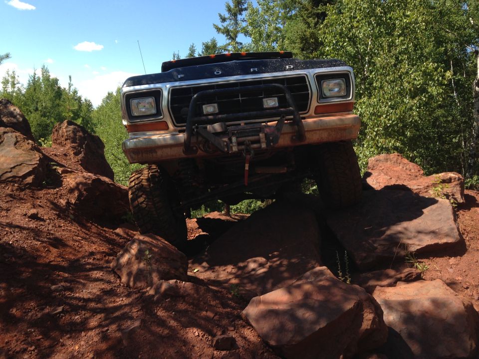 1979 Ford Bronco off-roading over large rocks, front view.