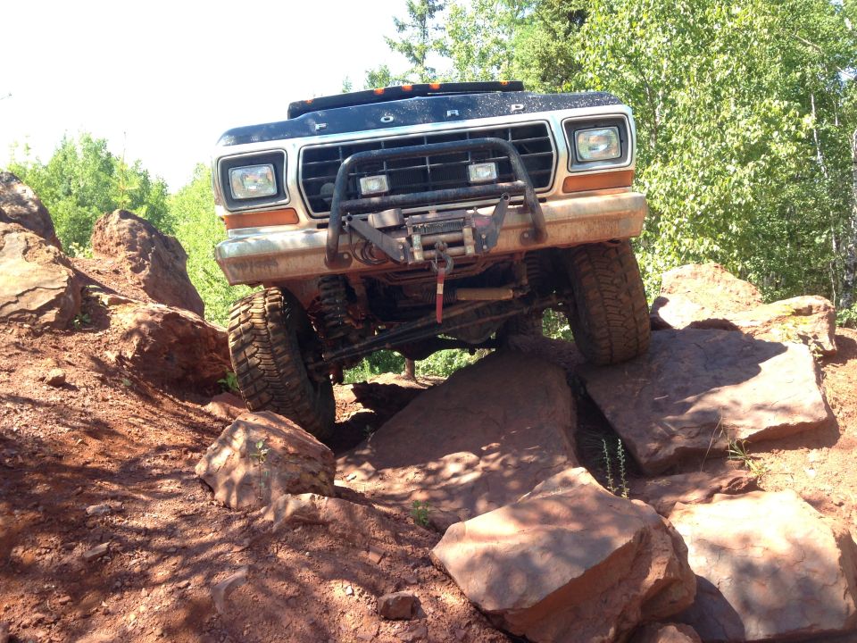 1979 Ford Bronco off-roading over large rocks.