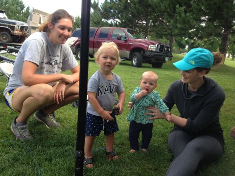 1979 Ford Bronco - Two women and two young children are gathered on a grassy lawn in front of a red Ford F-Series pickup truck. A black Ford Bronco is visible…