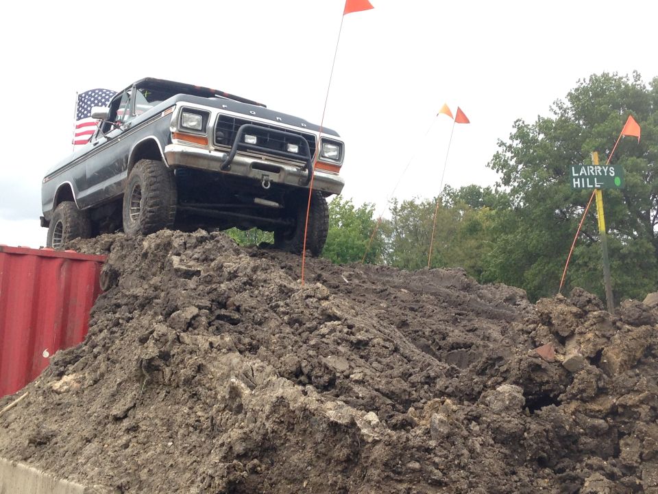 1979 Ford Bronco on a dirt mound with an American flag and orange flags in the background.