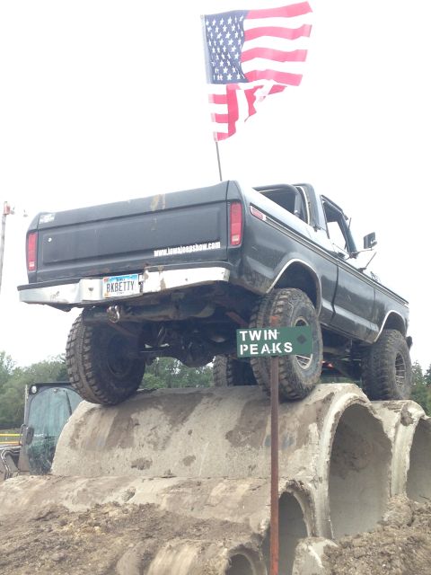 1979 Ford Bronco - This pickup truck, likely from the late 1970s, navigates an obstacle course with an American flag waving from its bed.