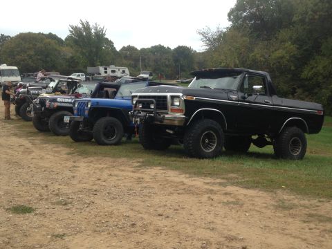 1979 Ford Bronco - Several off-road vehicles are parked in a grassy lot, with a black Ford Bronco in the foreground.
