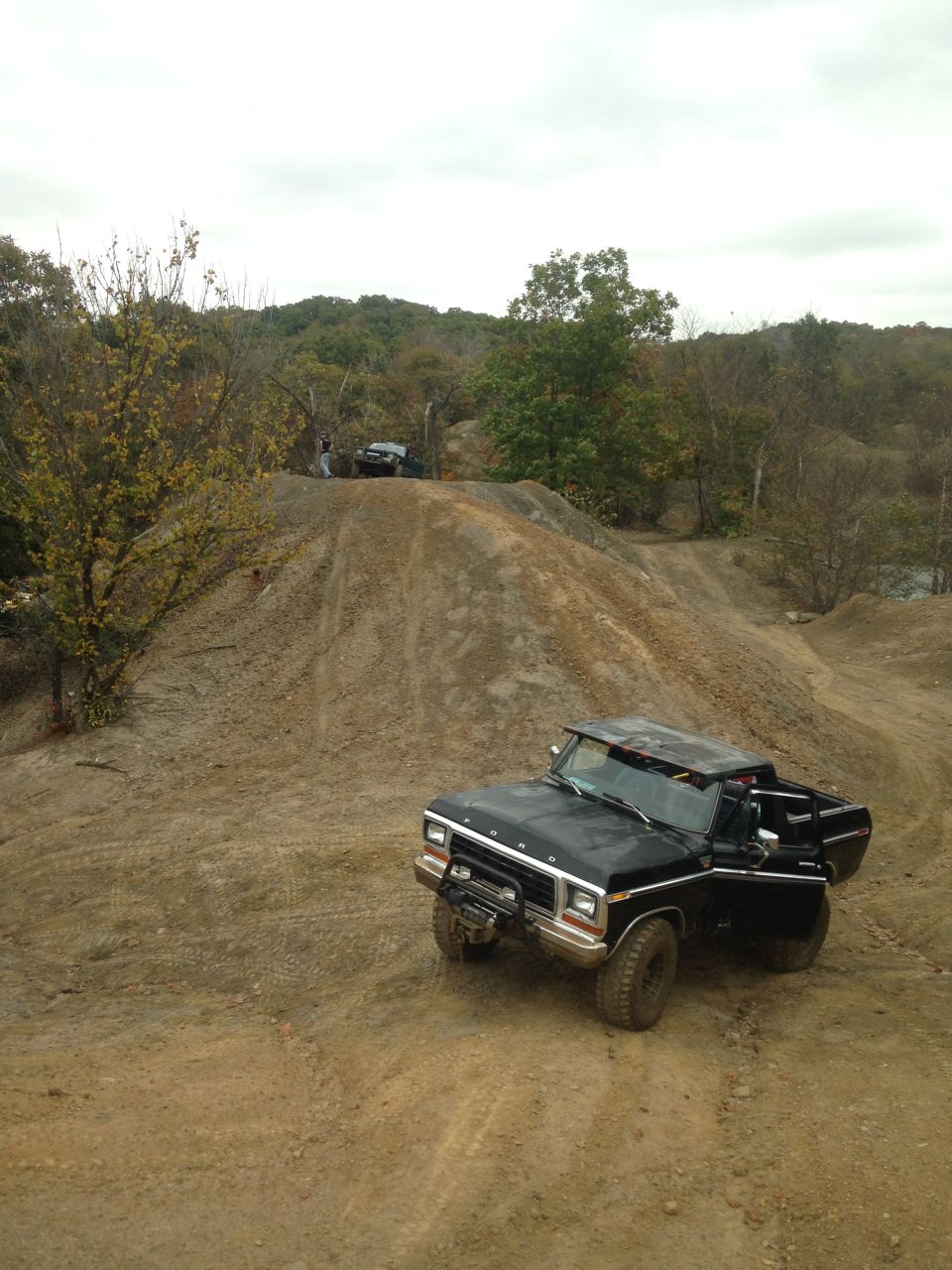 Black 1980s Ford F-Series truck on dirt hill, another vehicle in background