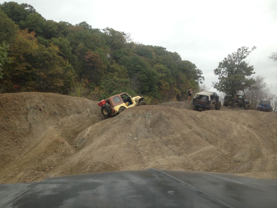 Several off-road vehicles navigating steep dirt hills under an overcast sky