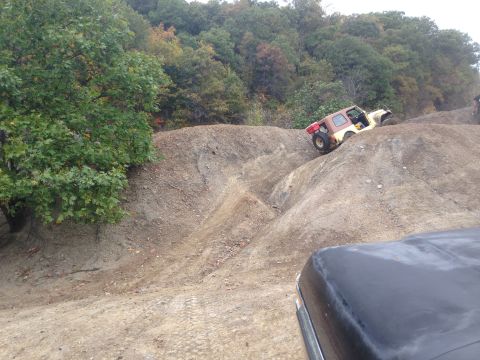 1979 Ford Bronco - An off-road vehicle navigates a challenging dirt incline, with another vehicle partially visible in the foreground.