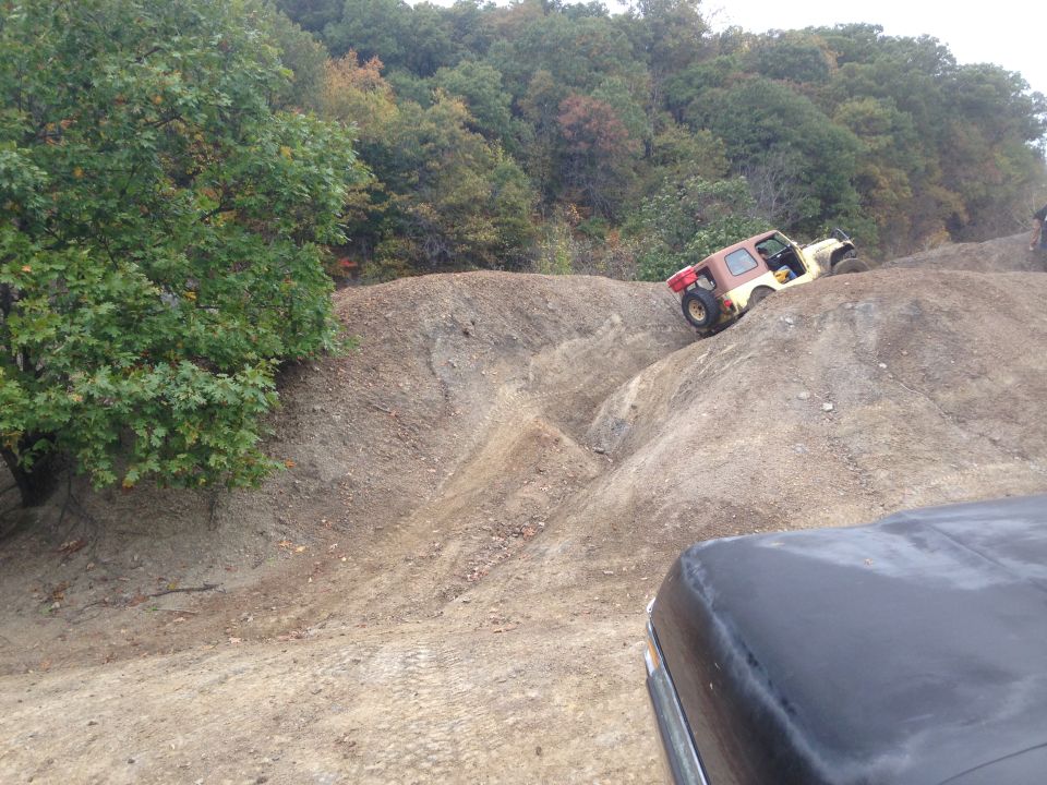 off-road vehicle climbing a steep dirt hill, another vehicle in foreground