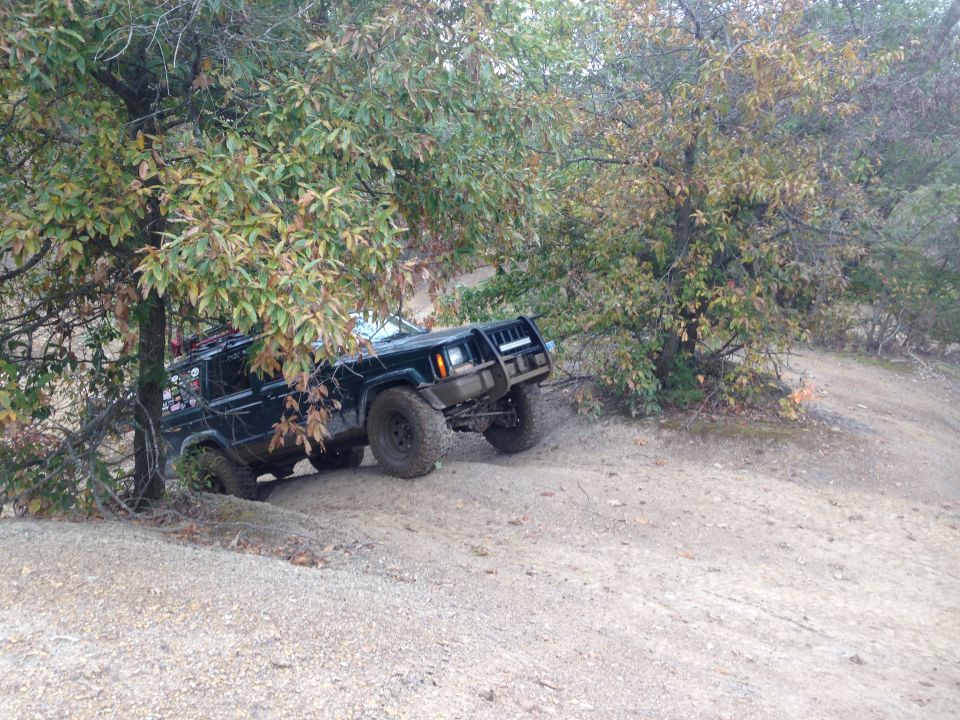 Black Jeep Cherokee XJ climbing a dirt hill off-road
