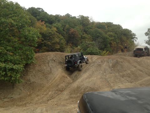 1979 Ford Bronco - Two off-road vehicles navigate a challenging dirt terrain with wooded hills in the background.