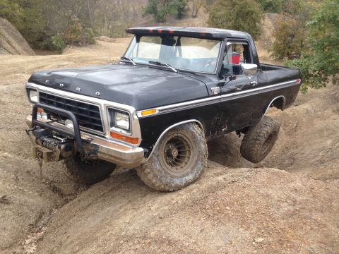 1979 Ford Bronco - This black Ford Bronco is navigating challenging off-road terrain.