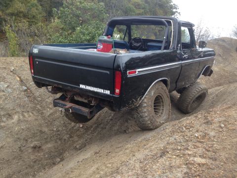 1979 Ford Bronco - Black Ford Bronco with roll cage navigating a dirt trail.