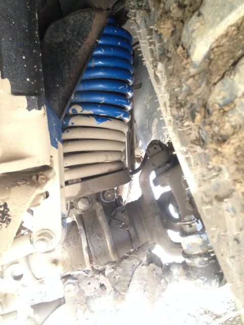 1979 Ford Bronco - This image shows a close-up view of a vehicle's suspension system, specifically a shock absorber, covered in dirt and mud.