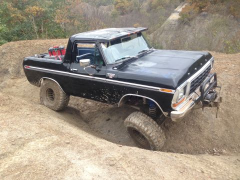 1979 Ford Bronco - This black 1979 Ford Bronco is shown off-roading on a challenging dirt path.