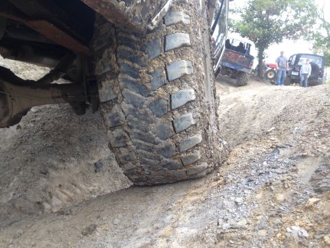 1979 Ford Bronco - Multiple off-road vehicles navigate a muddy incline, with a close-up on a heavily soiled tire.