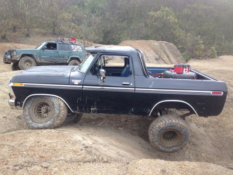 1979 Ford Bronco - Two off-road vehicles navigate a dirt trail with a pile of dirt in the background.