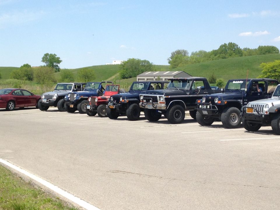 Black 1978 Ford F-Series truck parked in a lot with several Jeeps and a red sedan