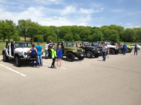 1979 Ford Bronco - A group of Jeeps are parked in a lot, with several people gathered around the vehicles.