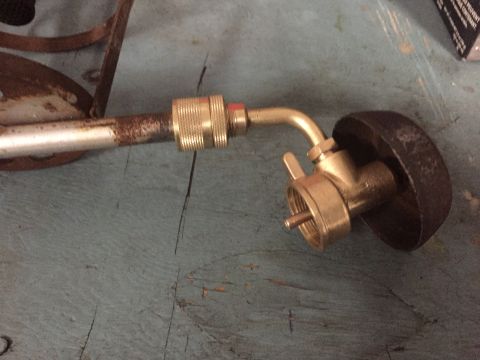 2014 Dodge 1500 - A close-up view of a brass torch fitting connected to a metal tube, resting on a blue surface.