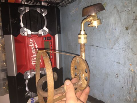 2014 Dodge 1500 - A Milwaukee radio is seen next to a rusty propane torch attachment, with a hand holding the attachment.