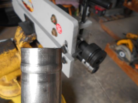 1992 Ford Bronco - A metal pipe is positioned in front of a pipe bending machine, with a circular saw visible in the background.