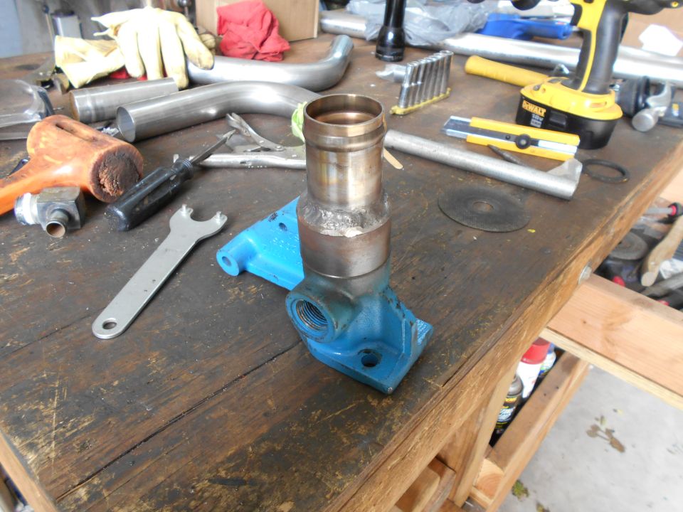 Workbench with various tools including a wrench, screwdriver, hammer, and a cordless drill, along with metal pipes and a blue bracket with a metal fitting