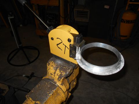 1992 Ford Bronco - A metal ring is being formed by a yellow tool clamped in a vise.