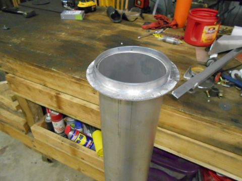 1992 Ford Bronco - A metal pipe with a flanged opening sits on a workbench, surrounded by tools and supplies.