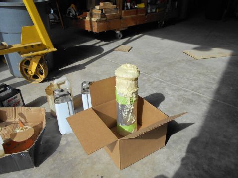 1992 Ford Bronco - Expanding foam is being applied to a pipe inside a cardboard box, with various containers nearby.