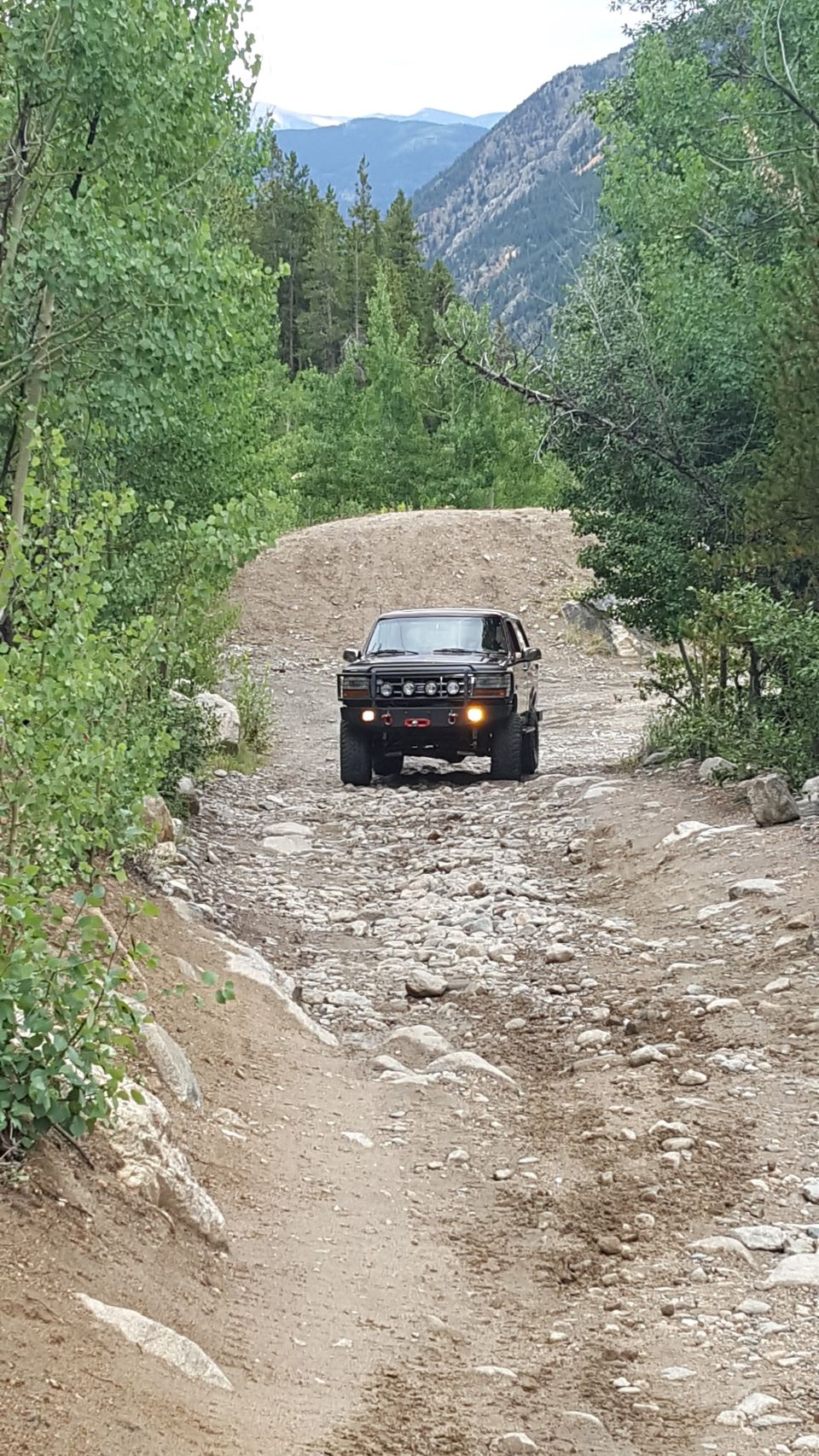 Black Ford Bronco driving on a rocky mountain road
