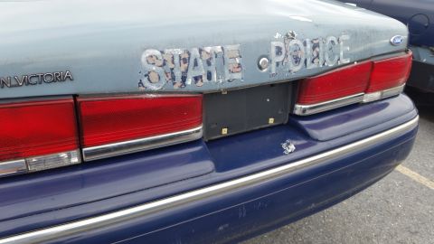 1991 Ford LTD Crown Victoria - Rear view of a 1991 Ford Crown Victoria police car showing "STATE POLICE" text and taillights.