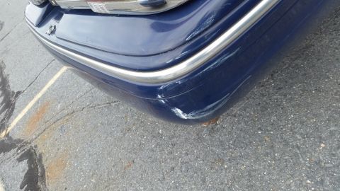 1991 Ford LTD Crown Victoria - The rear corner of a blue vehicle shows damage and scuffs on the bumper.