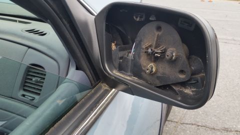 1991 Ford LTD Crown Victoria - The side mirror assembly has been detached, revealing the internal components and mounting hardware.