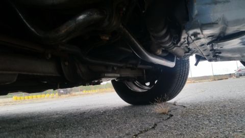 1991 Ford LTD Crown Victoria - A low-angle shot reveals the underside of a vehicle, focusing on the rear wheel and suspension system.