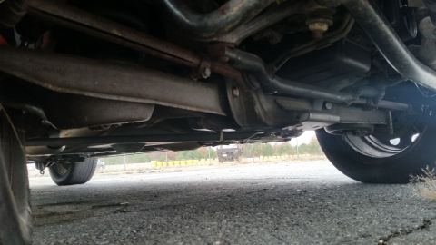 1991 Ford LTD Crown Victoria - A low-angle view of a vehicle's undercarriage, revealing suspension parts and the exhaust system.